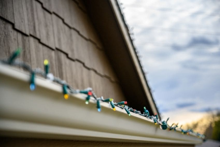 Will Christmas Lights Damage Gutter Guards? Christmas lights hanging on a gutter guard